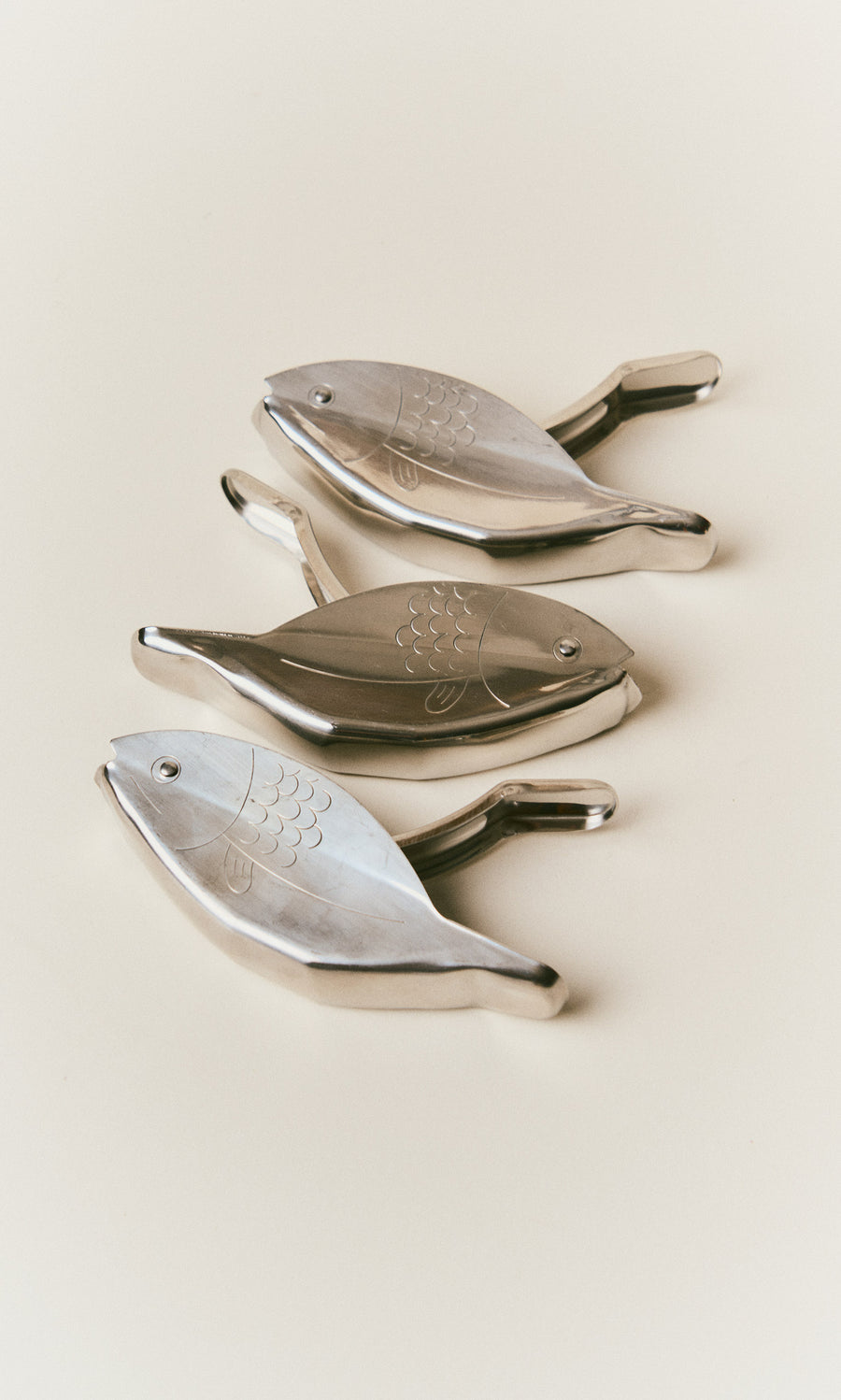 Plümo  Three metallic Fish Lemon Squeezer tools arranged diagonally.