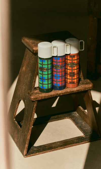 Plümo  Three Tartan Flask - Green flasks with white caps standing on a small wooden step stool.