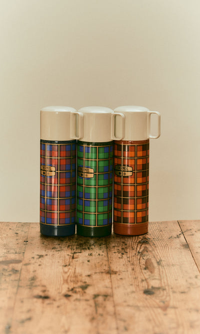Plümo  Three Tartan Flask - Blue vacuum flasks in blue, green, and orange patterns standing on a wooden surface.