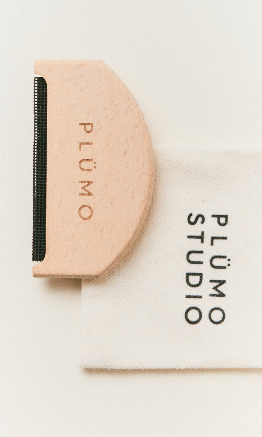 Plümo  A pink Wool Comb rests on white fabric, perfect for removing pilling from your favorite knitwear.