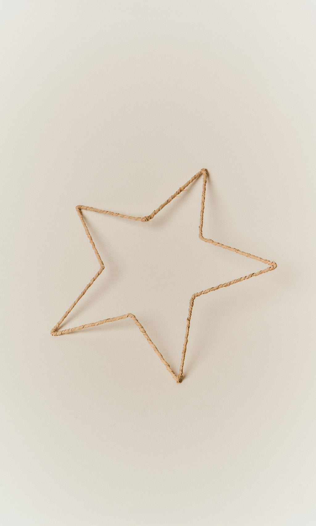 Plümo  Raffia Christmas Star, a five-pointed star ornament handmade from wrapped tan raffia.