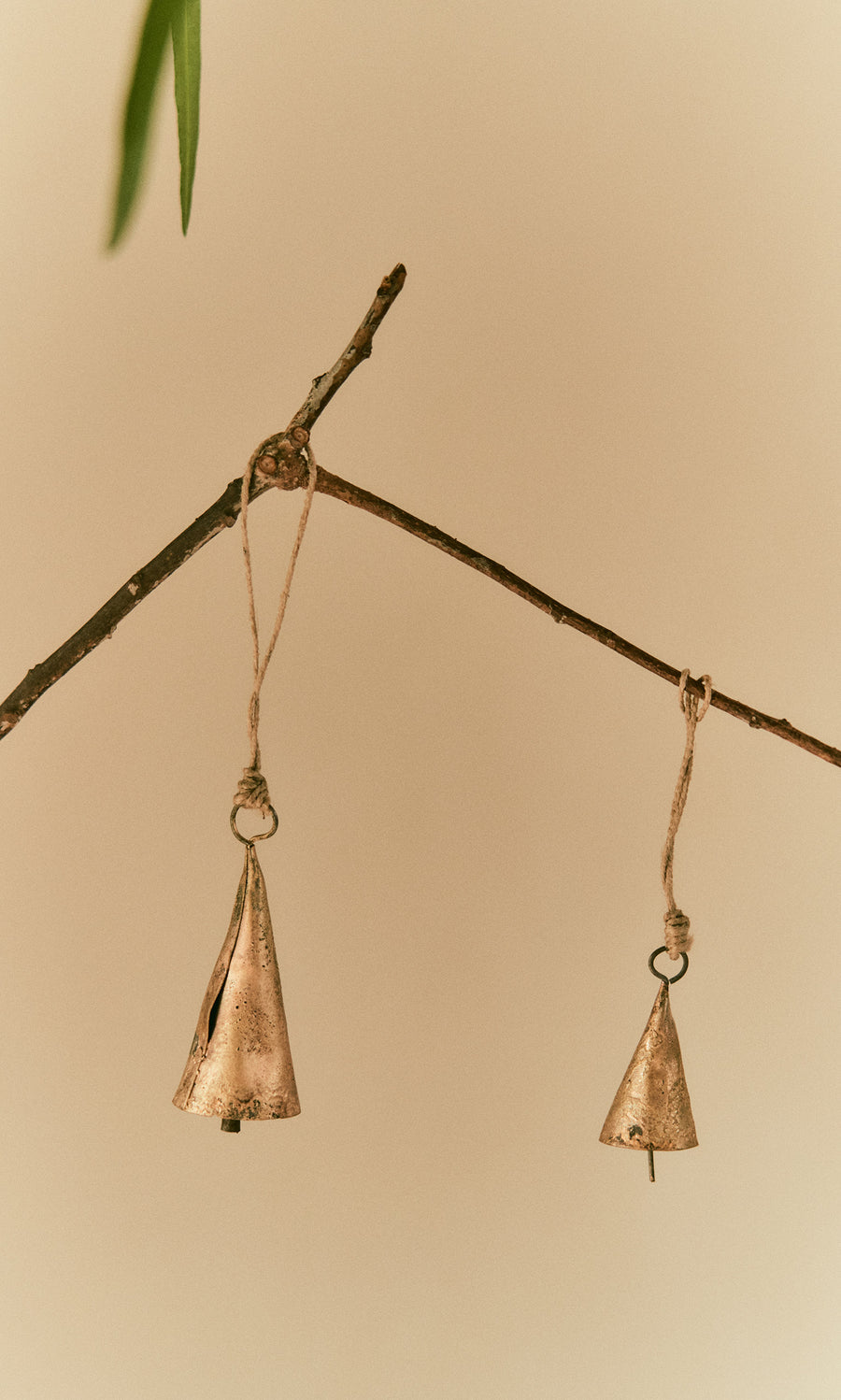 Plümo  Two Hanging Brass Bells - Small dangle from twine, chiming softly against a neutral beige background.