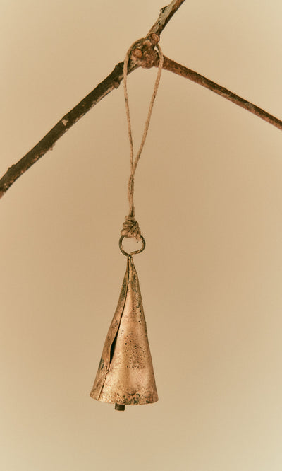Plümo  A Hanging Brass Bell - Medium hangs by a string from a branch against a plain, light background.