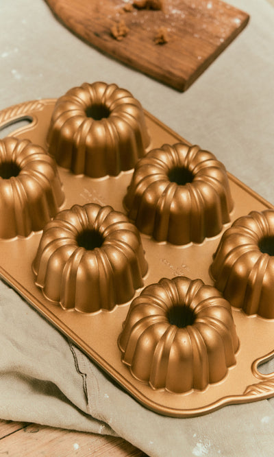Plümo  A gold-colored, non-stick Bundtlette Form with six circular, fluted molds.