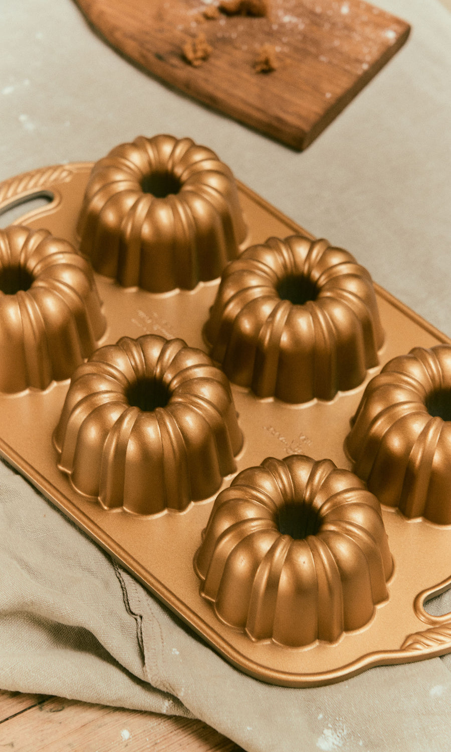 Plümo  A gold-colored, non-stick Bundtlette Form with six circular, fluted molds.