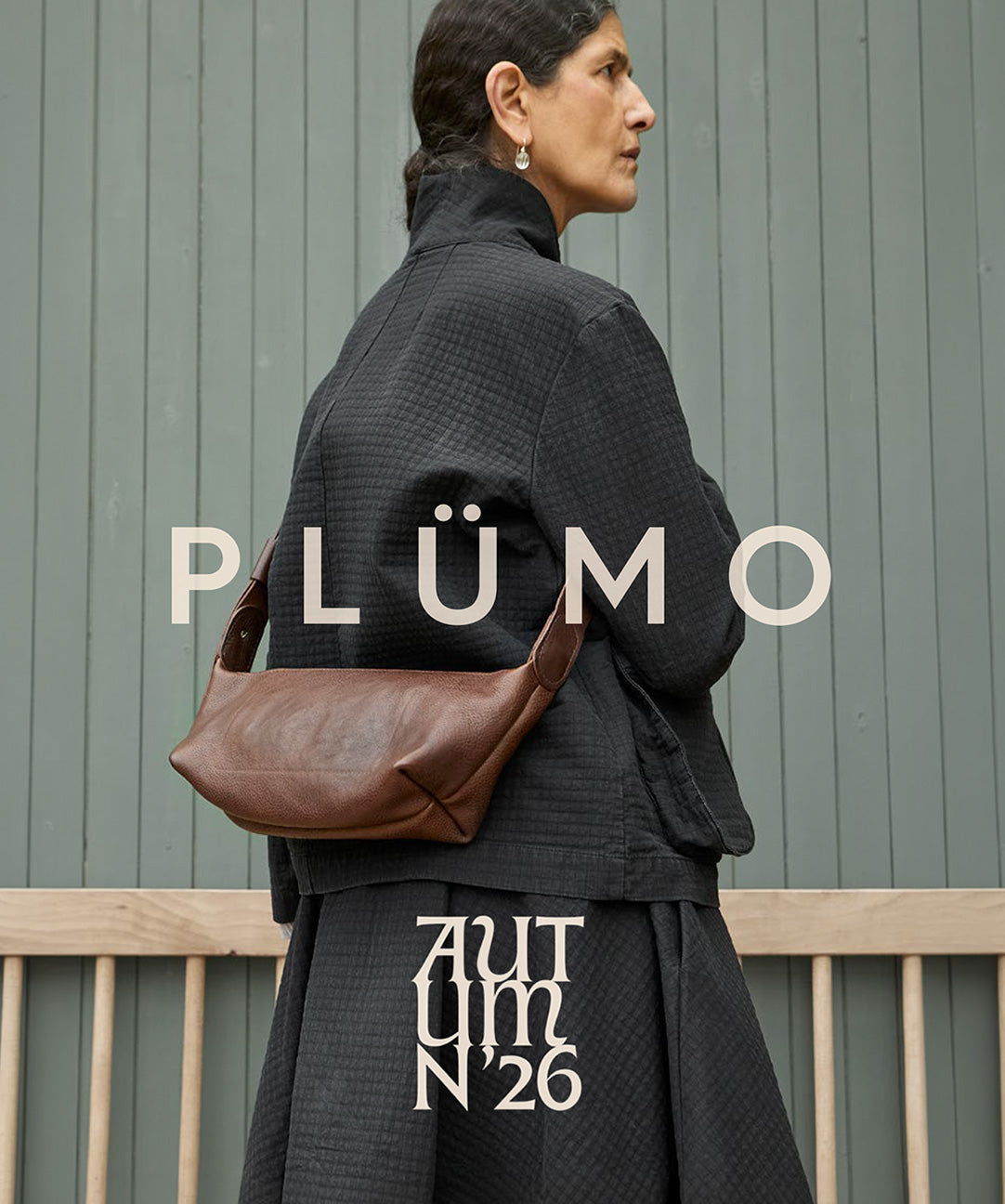 Plümo  Woman in dark clothing with a brown bag over her shoulder, PLÜMO AUTUMN 26 text overlaid.