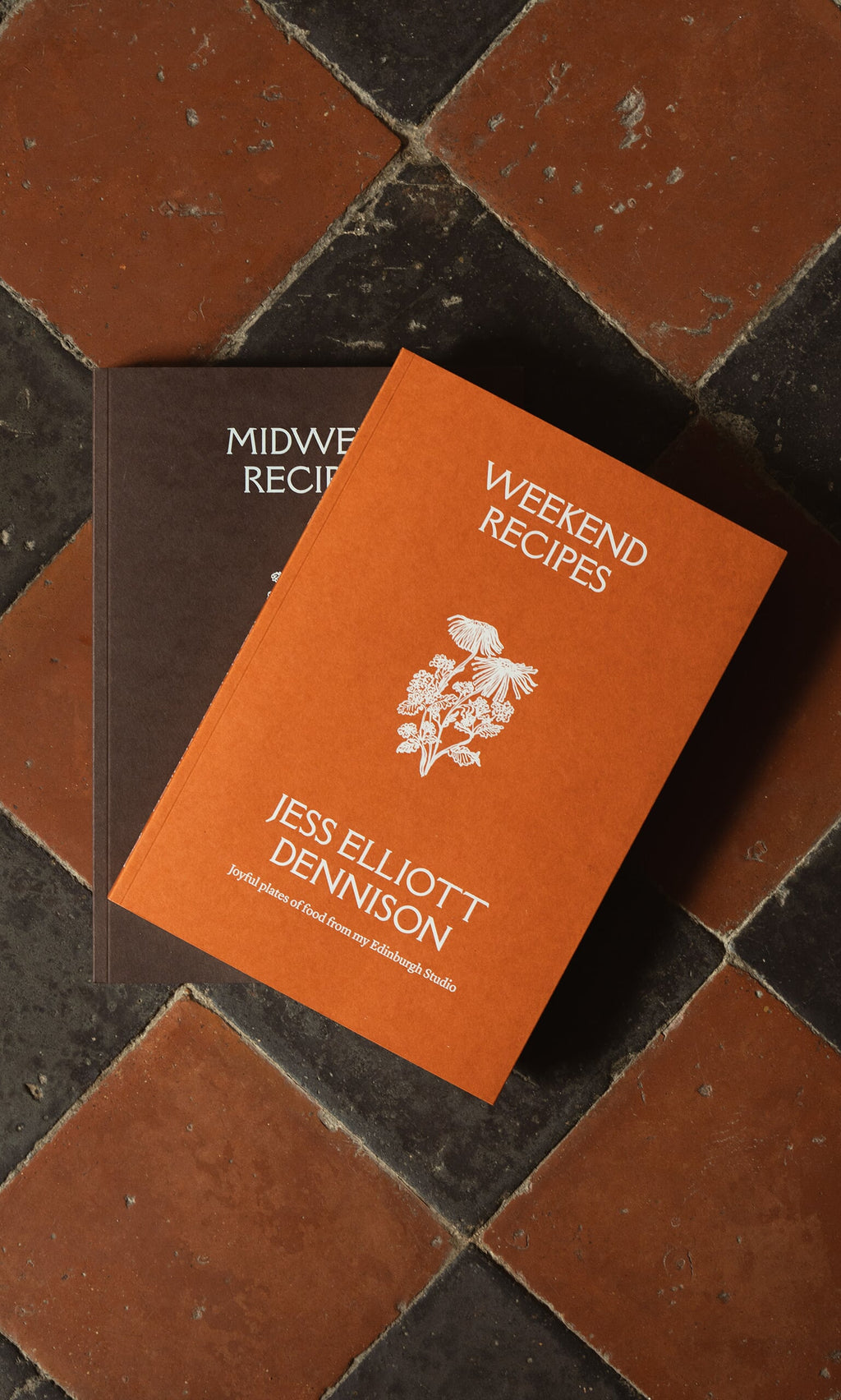 Plümo- Cookbook, Weekend Recipes by Jess Elliott Dennison, ideal for weekend cooking, displayed on a tiled floor.