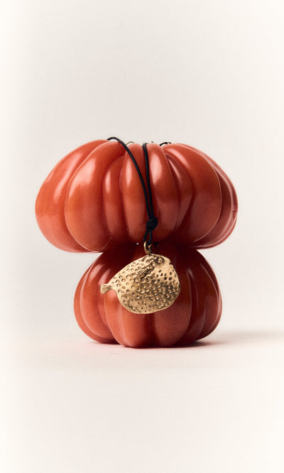 Plümo- Two stacked tomatoes with a handcrafted Puffer Fish Necklace draped over them, against a white background.