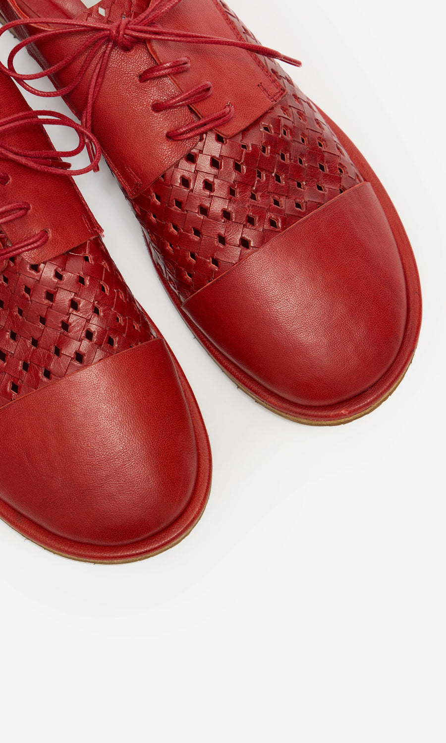 Plümo- Close-up of Magui Brogues—red Italian leather shoes with woven details and laces, set against a white background.