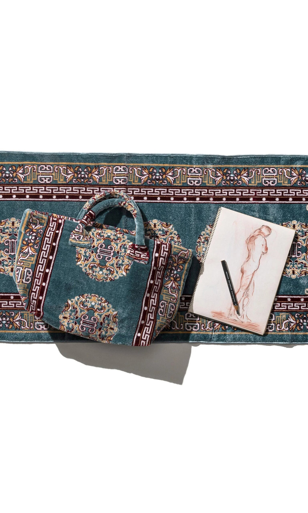 Plümo- Persian Blue Rug Bag with matching mat next to a sketchbook featuring a figure drawing and pen on white background.