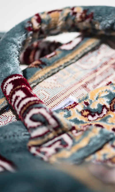 Plümo- Close-up of the Rug Bag - Persian Blue handle featuring intricate red, blue, yellow, and beige woven designs.