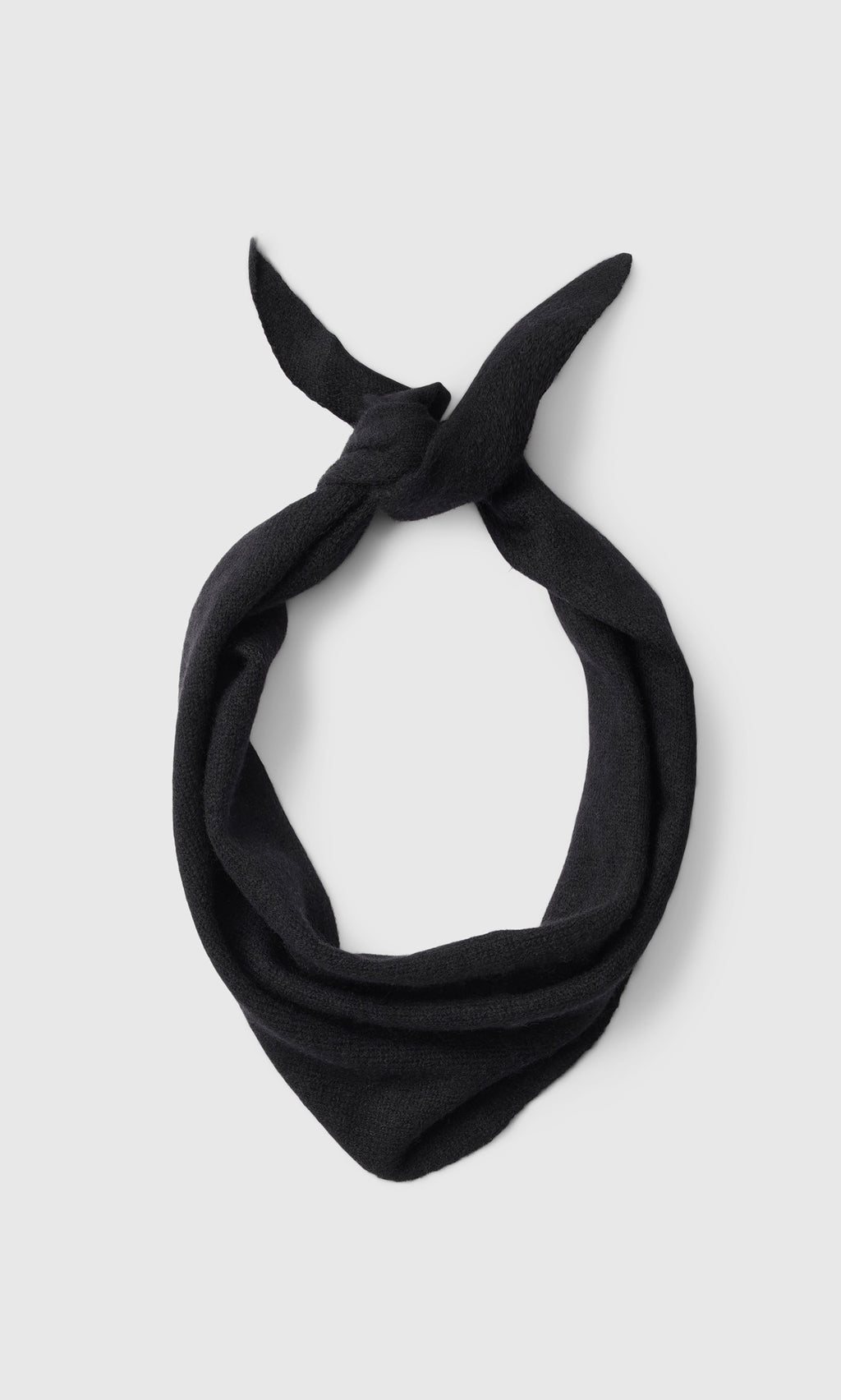 Plümo  A Black Cashmere Necktie, tied simply and inspired by Danish design, rests on a plain light gray background.