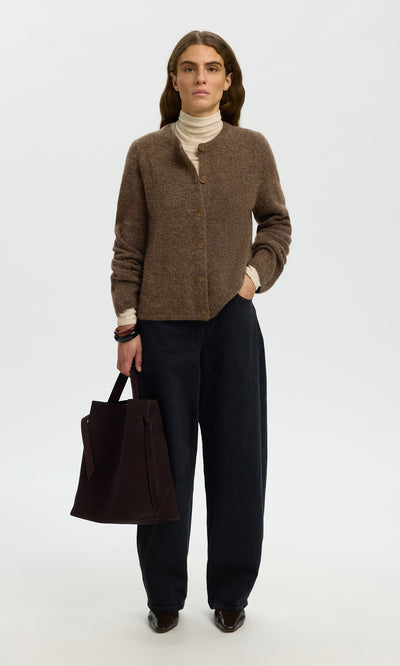 Plümo  Woman in a Findlay Cardigan, cream turtleneck, wide-leg pants, holding a dark tote against a white backdrop.