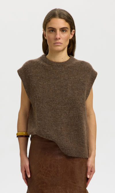 Plümo  Woman layering the Rennes Tank Top in peat brown over a skirt, standing against a plain light background.