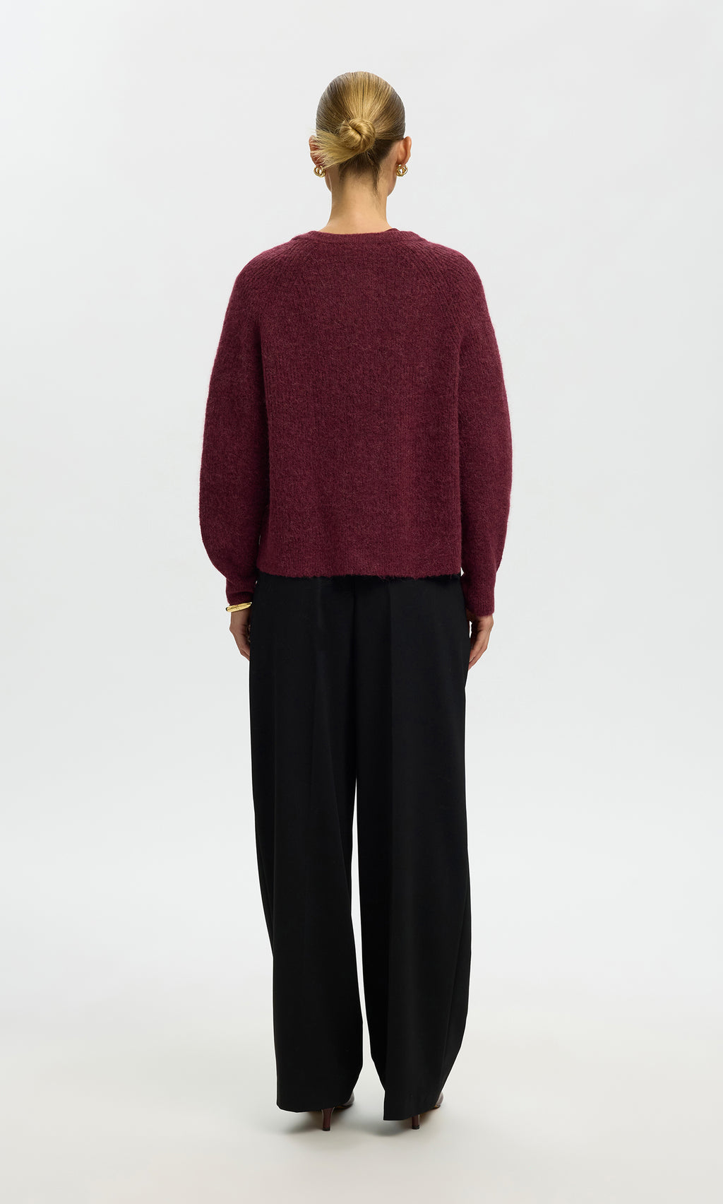 Plümo  Model faces away in the Caen Cardigan - Jam and loose black pants against a plain white background.