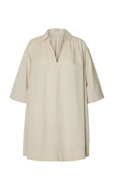 Plümo- The Cory Tunic is a beige, loose linen smock dress with a V-neck, 3/4 sleeves, and a relaxed A-line shape.
