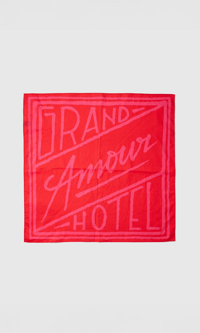 Plümo- The Poinsettia Necktie is red and pink with "Grand Amour Hotel" in bold, stylized letters.