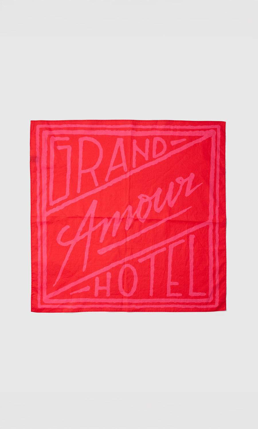 Plümo- The Poinsettia Necktie is red and pink with "Grand Amour Hotel" in bold, stylized letters.