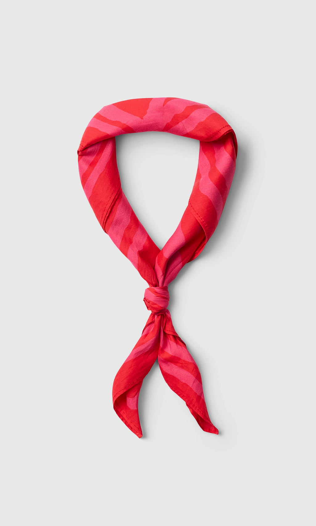 Plümo- Poinsettia Necktie in red and pink pattern, loosely knotted and displayed on a light gray background.