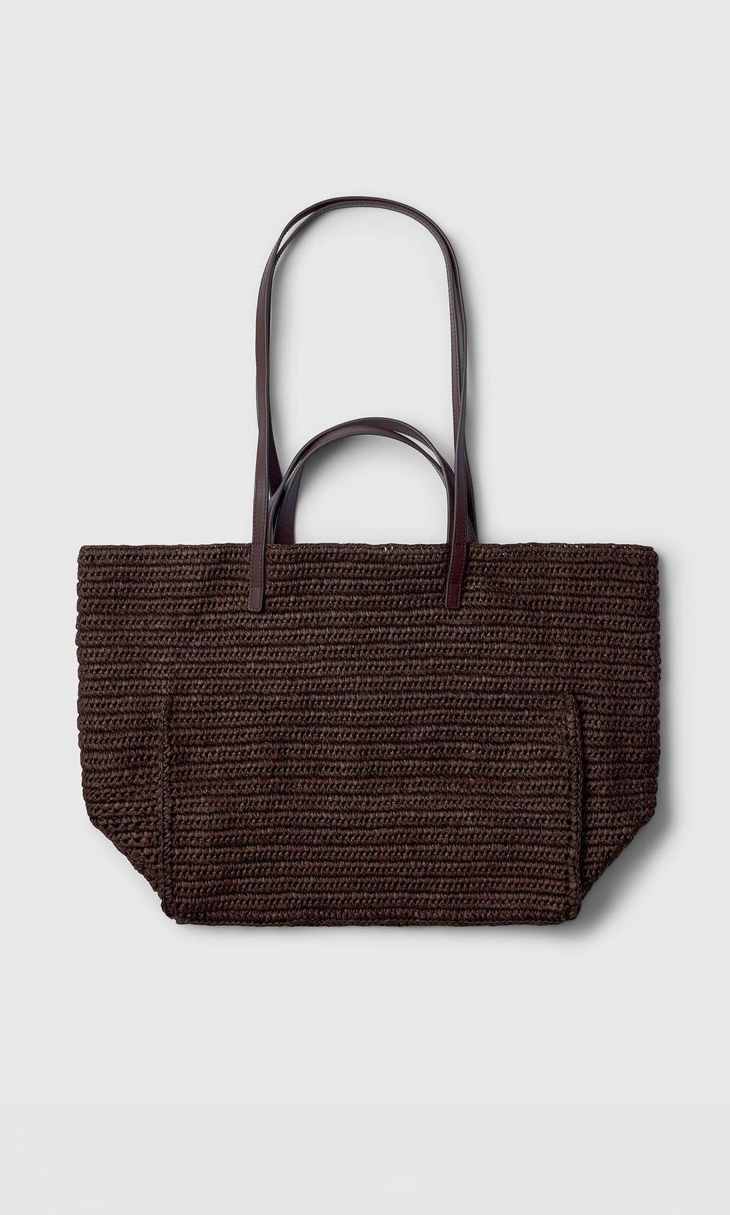 Plümo- The Tova Bag, a dark brown straw tote with long handles, is shown on a plain light gray background.