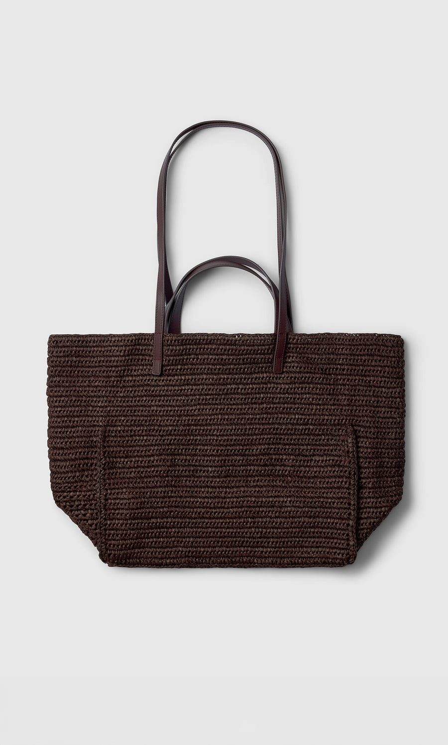 Plümo- The Tova Bag, a dark brown straw tote with long handles, is shown on a plain light gray background.