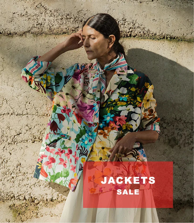 Plümo  A woman in a colorful floral jacket stands against a textured wall. Text reads: JACKETS SALE.