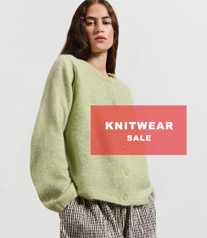 Plümo  Woman in a green knit sweater and checkered pants with a Knitwear Sale banner overlaying the image.