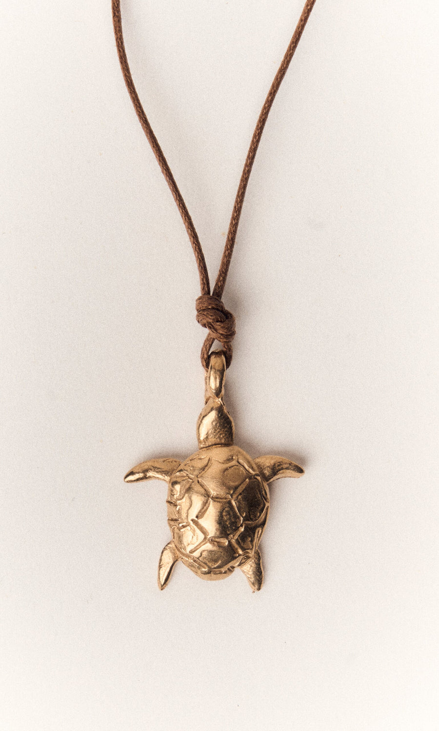 Plümo- The Sea Turtle Necklace features a handcast bronze turtle pendant on a brown cord, inspired by Florence, Italy.