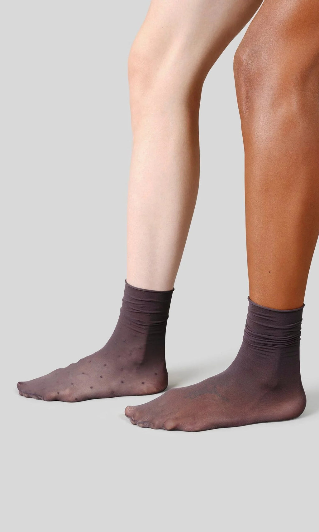 Plümo- Two people wear Sheer Grey Socks, semi-sheer and 20 denier, standing side by side on a grey background.