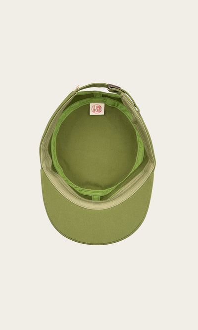 Plümo- Top view of the green Tsuba Cap, Hanpu canvas with curved brim and interior tag, handmade in Kyoto on off-white background.