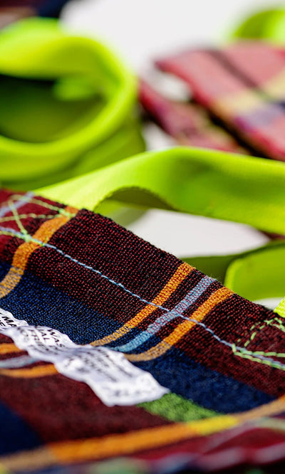Plümo- Close-up of the Tartan Document Holder, featuring bright yellow-green handles and recycled checkered fabric.