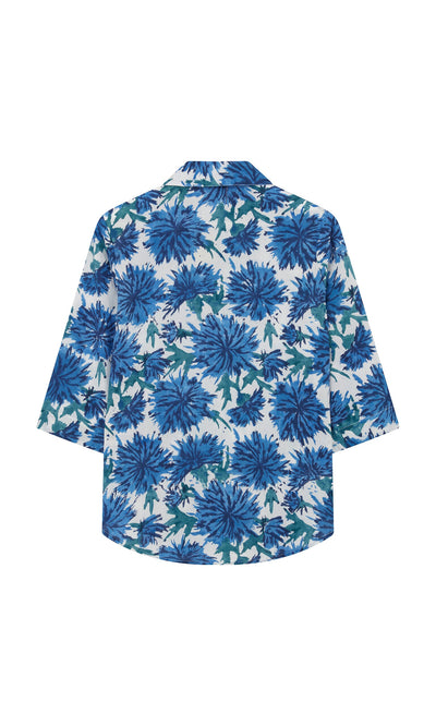 Plümo- Blue Thistle Shirt: block-print thistle flowers, blue and green, short sleeves, shell buttons, collar, back view.