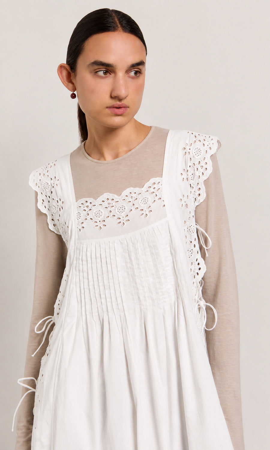Plümo  Woman in a beige top and Vintage Lace Dress - White, looking to her left.