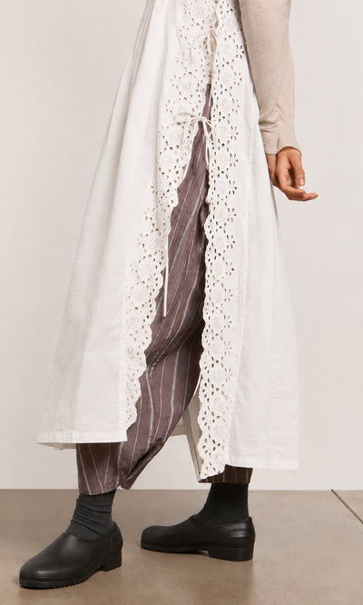 Plümo  Person wearing a Vintage Lace Dress - White over brown pinstriped pants with black socks and black shoes.
