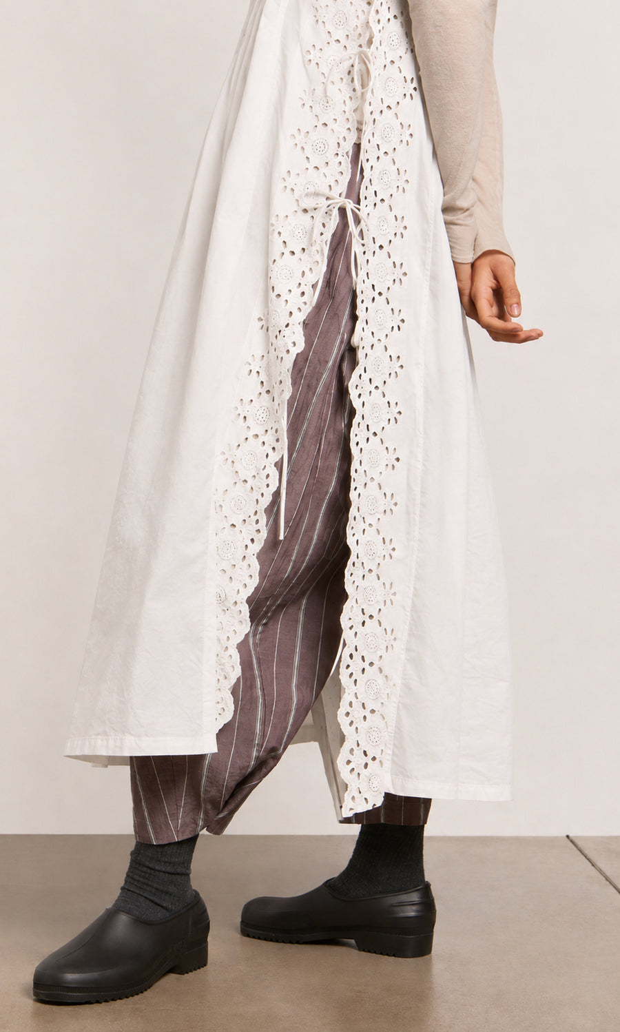 Plümo  Person wearing a Vintage Lace Dress - White over brown pinstriped pants with black socks and black shoes.
