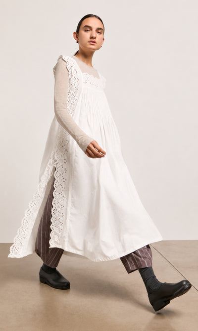 Plümo  Person in a Vintage Lace Dress - White, striped pants, and black shoes walks against a plain background.