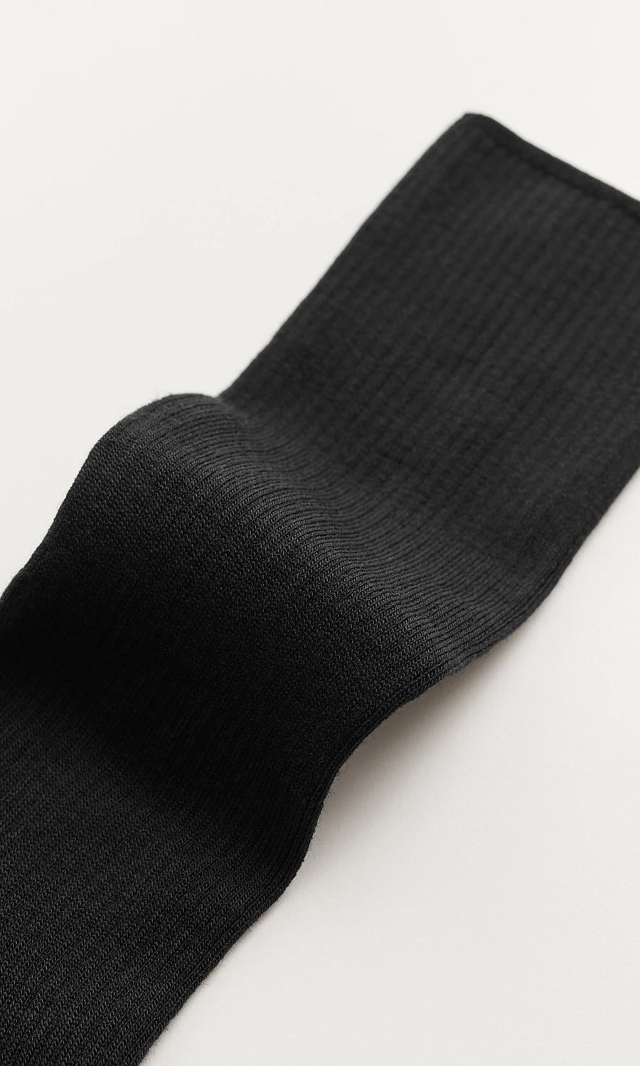 Plümo- Close-up of Black Rib Socks laid flat, showcasing their breathable knit fabric.