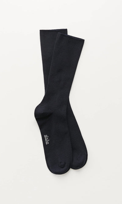 Plümo- A pair of Navy Rib Socks with "merci" in white near the toes, laid flat on a white background.