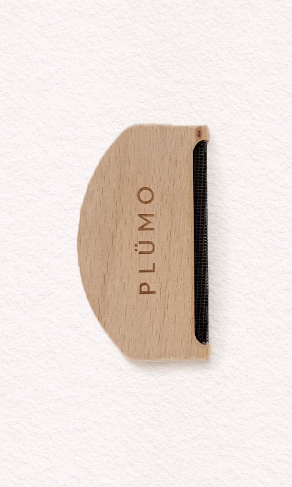 Plümo  The Wool Comb, with PLÜMO engraving and metal edge, removes pilling; shown on white background.
