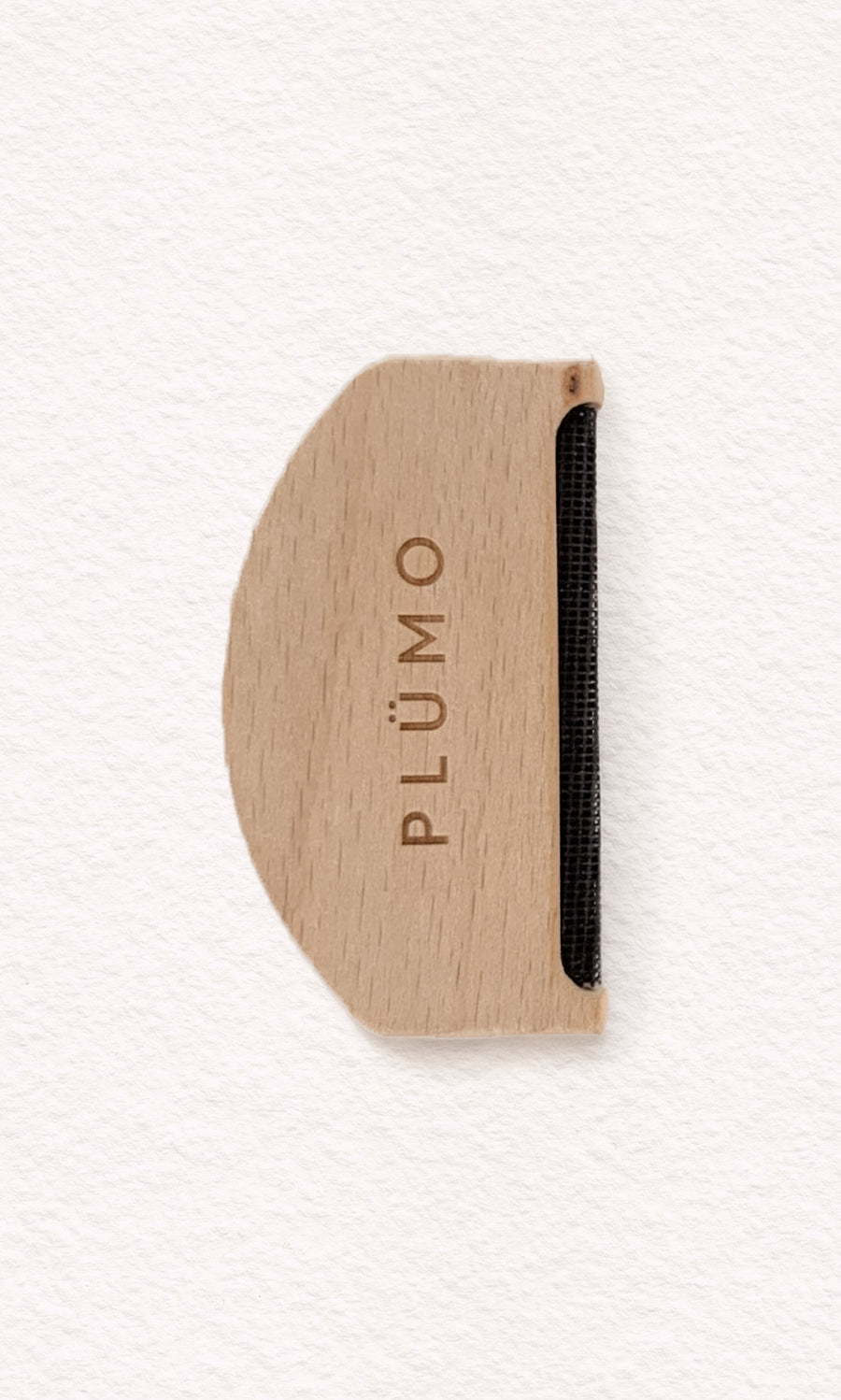 Plümo  The Wool Comb, with PLÜMO engraving and metal edge, removes pilling; shown on white background.