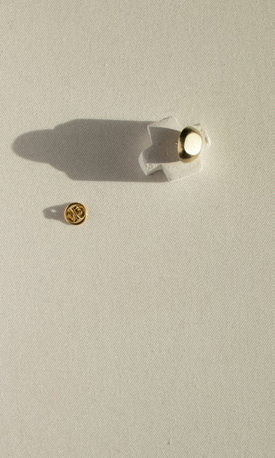 Plümo- The Amara Brooch, with its round gold back, rests on a white textured surface casting a subtle shadow.