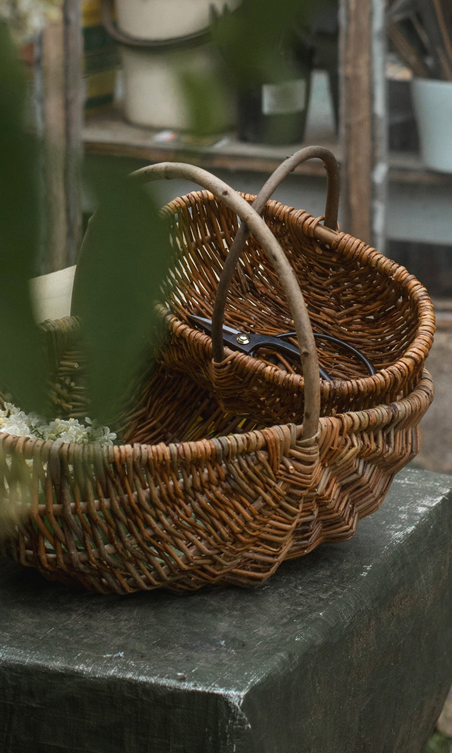 Plümo- Two woven baskets with handles sit on a table; Higurashi scissors are visible inside one basket.