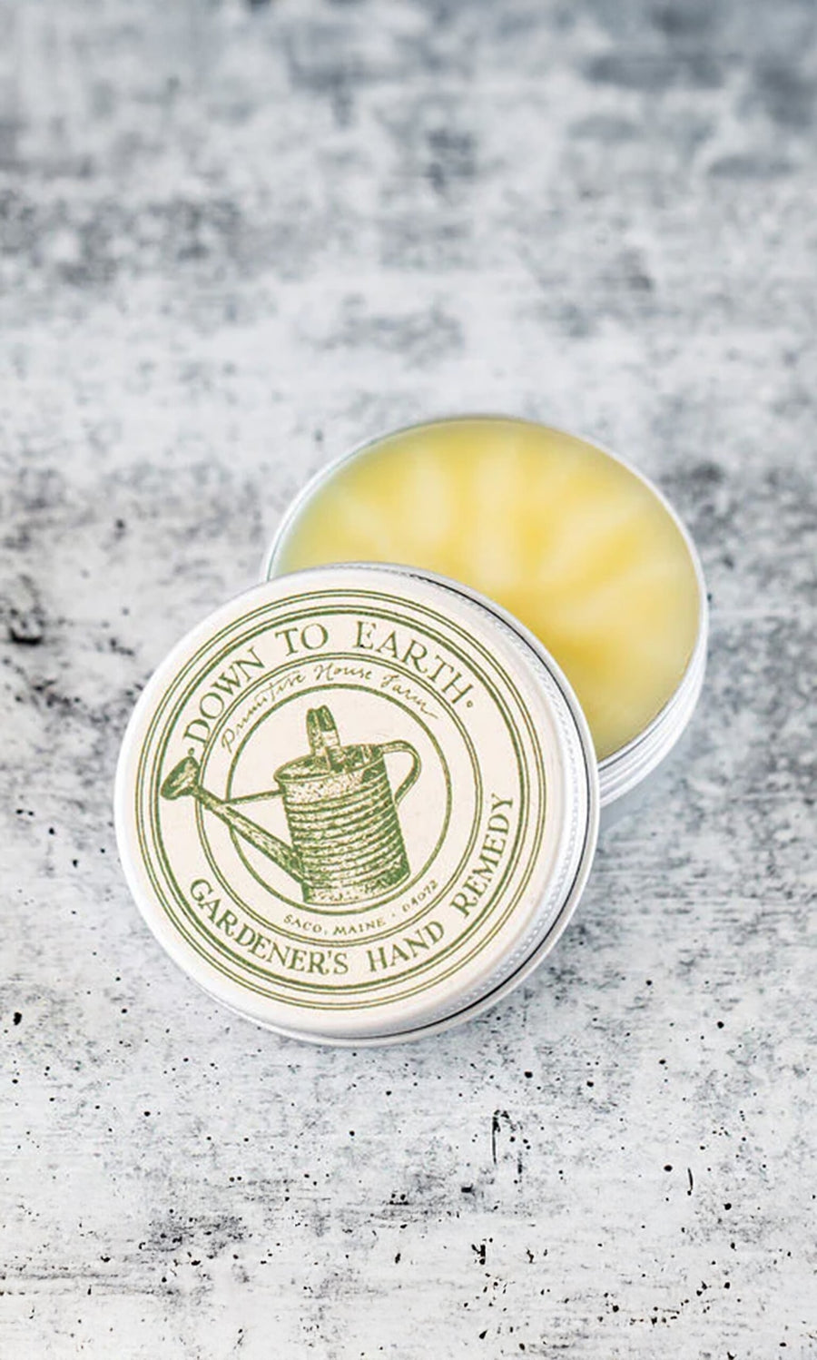 Plümo- A tin of Gardener's Hand Remedy with herbal ingredients, lid partially open to reveal the balm inside.