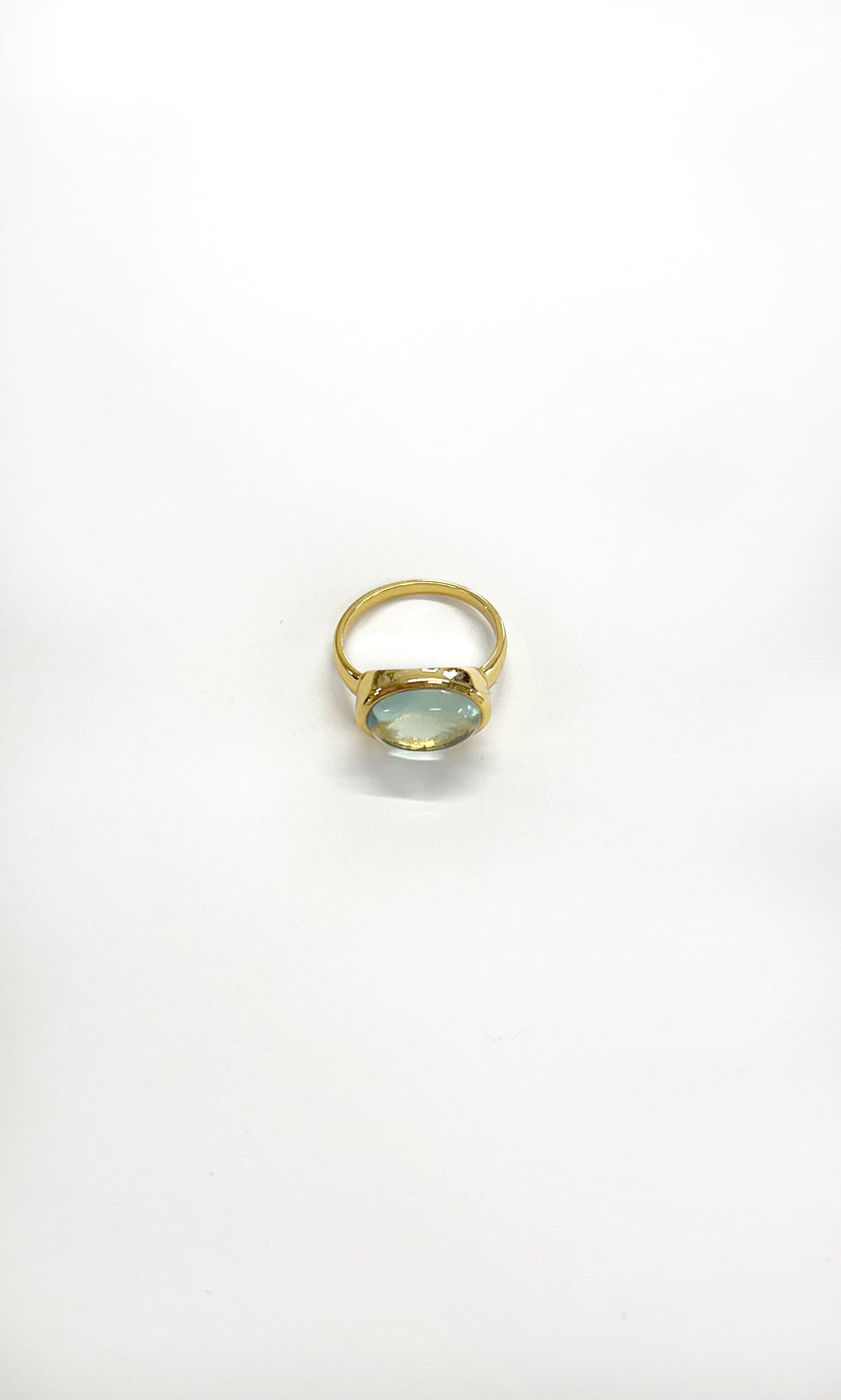 Plümo- The Alice Ring: a gold-plated ring with an oval blue gemstone in a bezel setting on a white background.