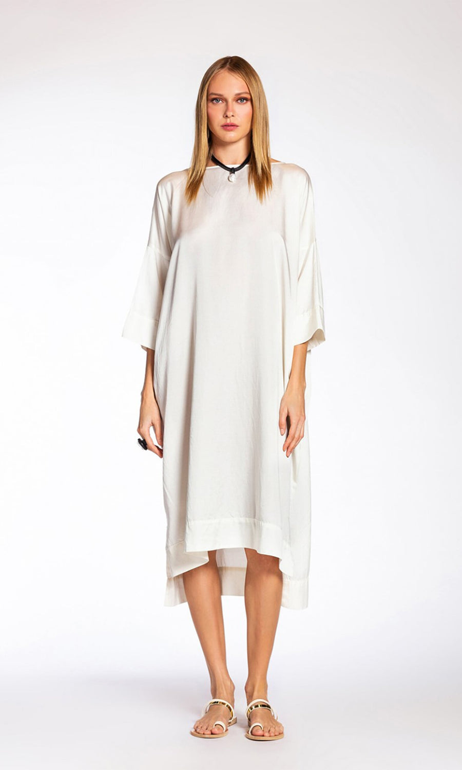 Plümo- Woman wearing the Arlen Dress and sandals, standing against a plain white background.