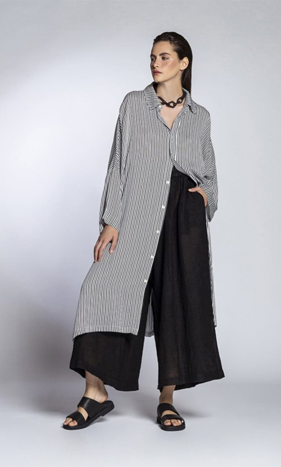 Plümo- Woman wearing the Mabel Stripe Dress with black wide-leg pants, sandals, and a chunky necklace.