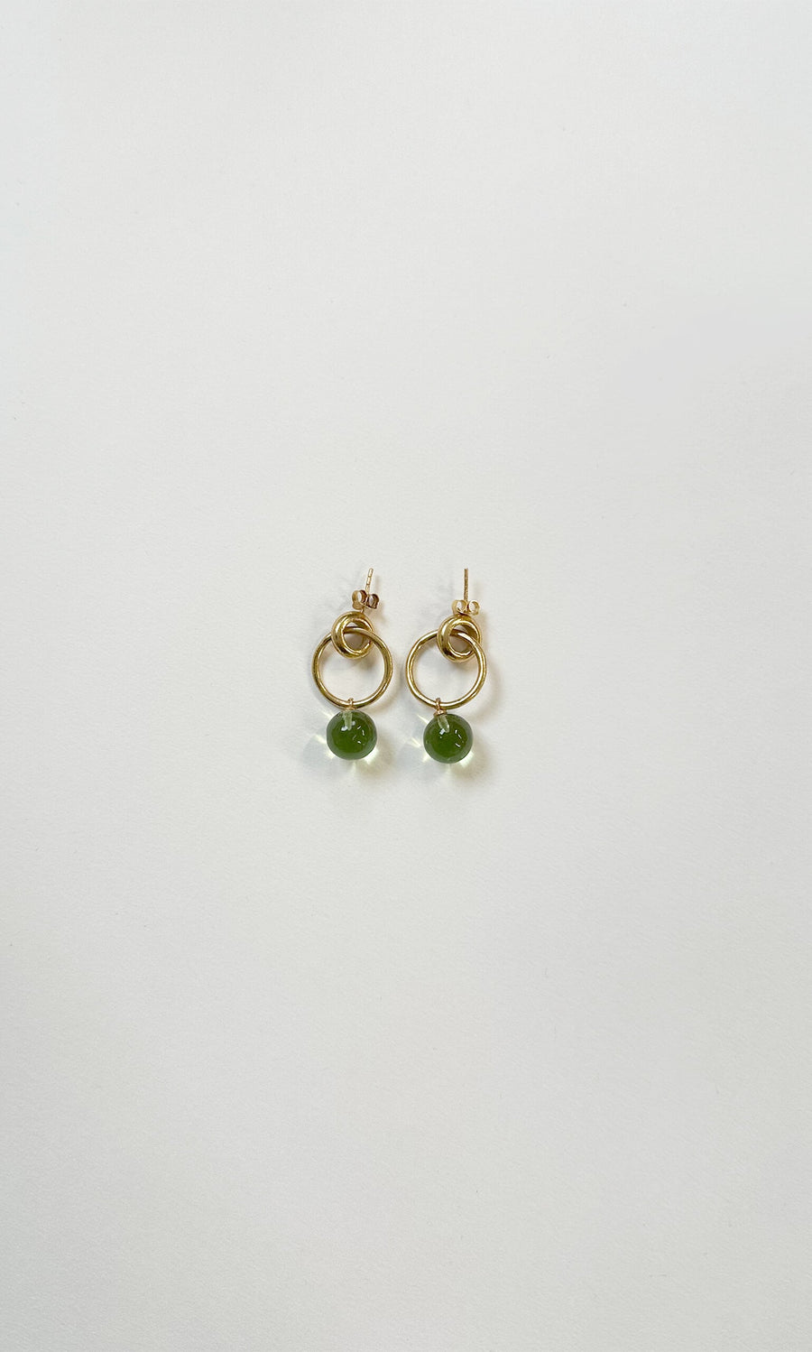 Plümo- Maggie Circle Studs: Gold hoop earrings with small green crystal spheres, handmade in London on a white background.