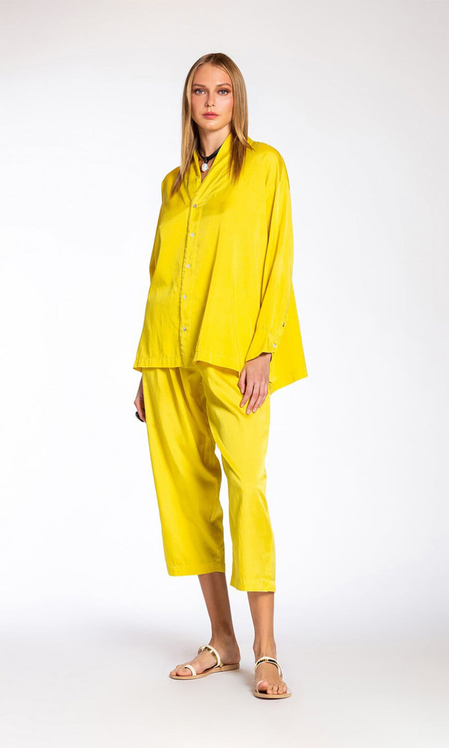 Plümo- A woman stands in a relaxed pose wearing the Marigold Shirt and matching cropped pants with sandals.