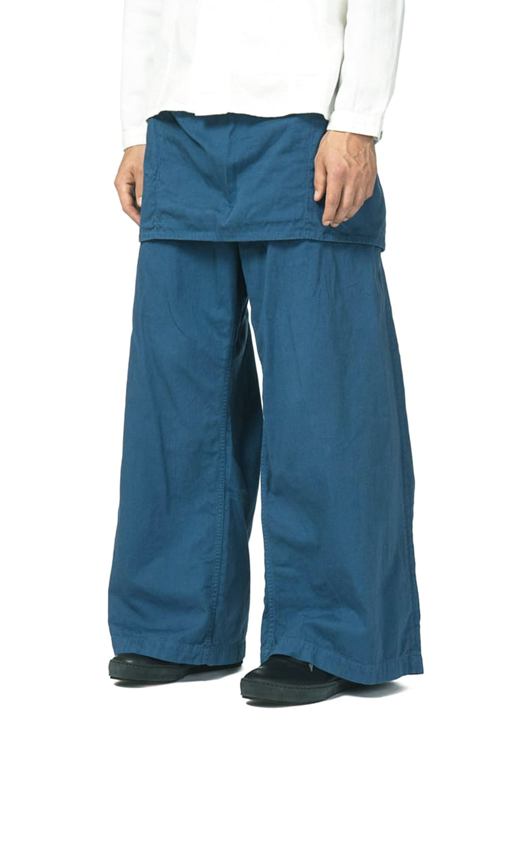 Plümo- Person wearing Raku Japanese Gardening Pants with apron-like flap and a crisp white shirt; hands by their sides.