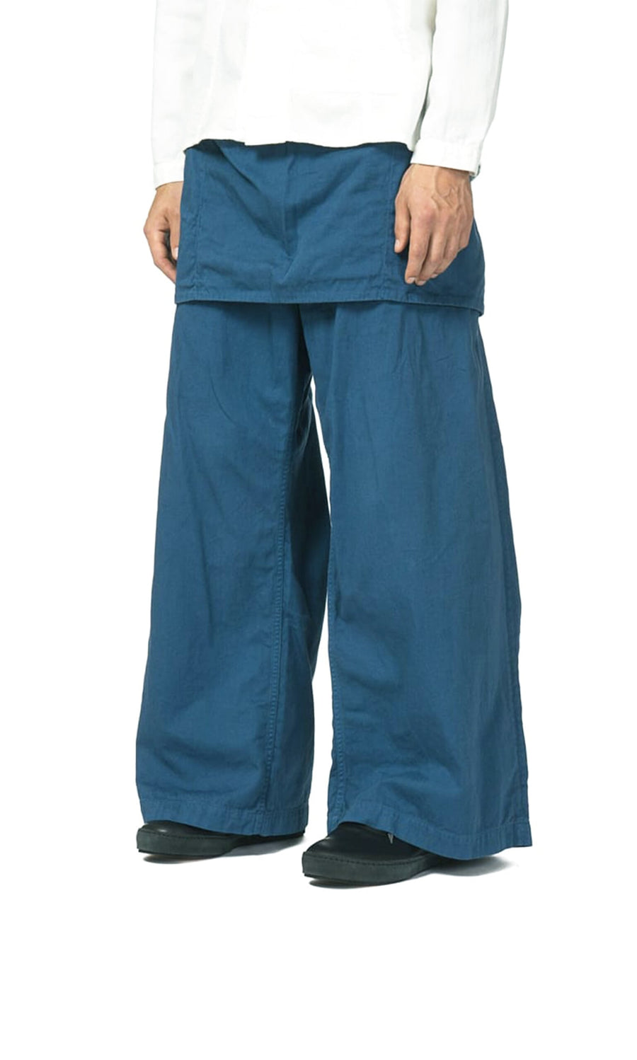 Plümo- Person wearing Raku Japanese Gardening Pants with apron-like flap and a crisp white shirt; hands by their sides.